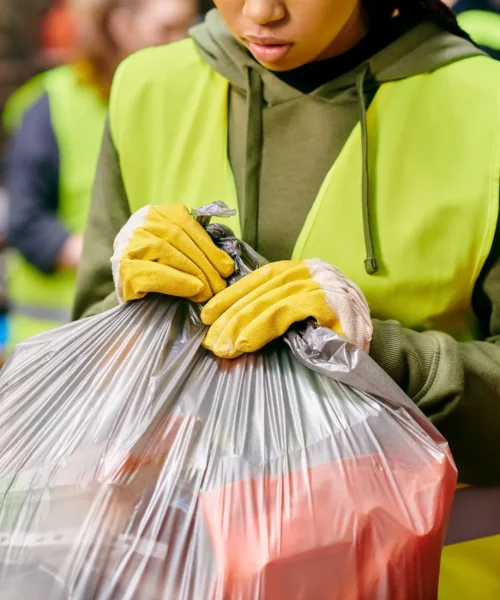 A girl carefully closing the plastic bag with junk inside.